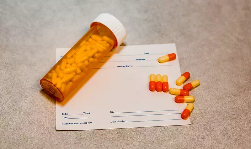 Pills and pill bottle laying on prescription