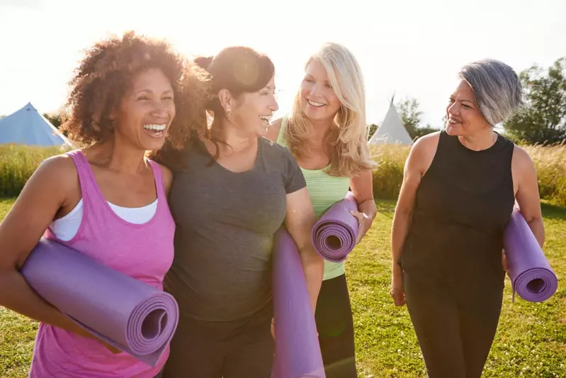 Smiling women outside with yoga mats