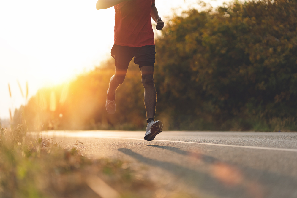 a man running on the side of the road for exercise at sunset