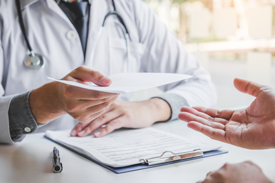 doctor filling out a medical prescription for a patient