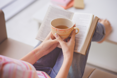 female reading a book with a cup of tea 