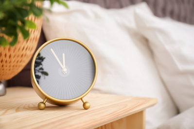 analog clock sitting on a bedside table 