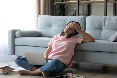 woman sitting on the floor falling asleep at her laptop