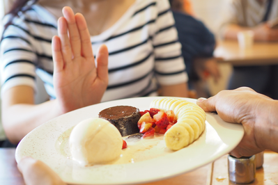 woman pushing a plate of food away