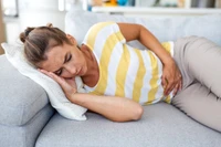 woman laying on couch with bloating